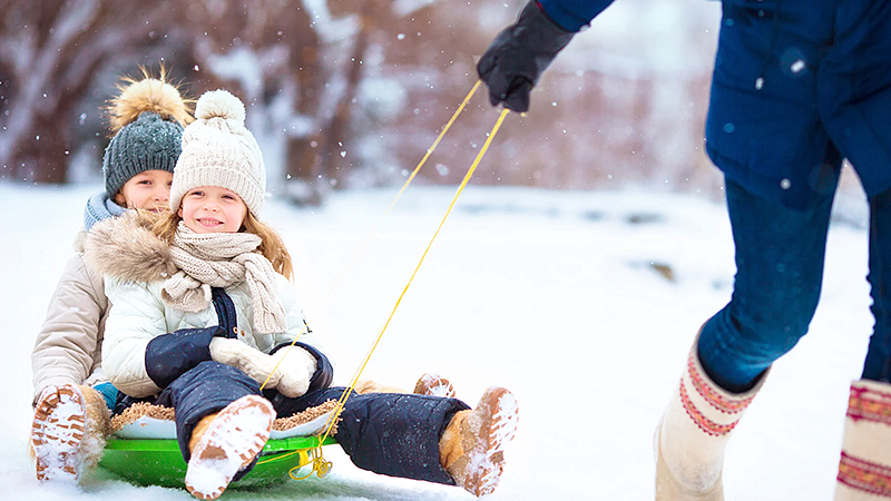 individual pulling children on a sled in the snow