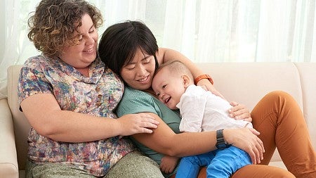 individuals sitting and cuddling while holding a baby