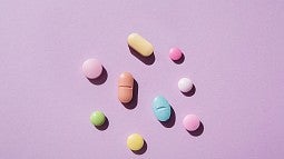 image of a variety of pills laying on a pink background