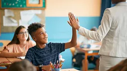 image of an individual greeting a student by giving a high five