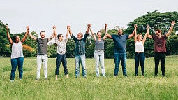 individuals standing in a grass field holding hands above their heads