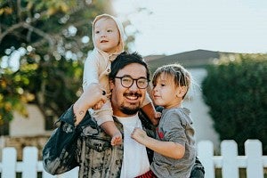 Man in white shirt carrying two children