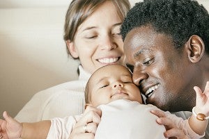 Two parents cuddle a baby
