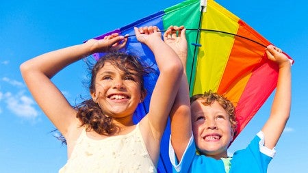Girl and boy holding rainbow kite Girl and boy holding rainbow kite