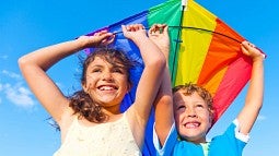Girl and boy holding rainbow kite